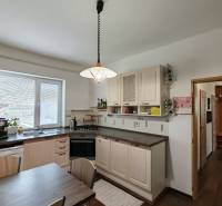 Konyha a családi házban világítással, mosogatóval, mosogatógéppel és asztallal, fa dekorációjú padlóval.