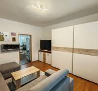 Nappali egy családi házban, fa mintázatú padlóval, kanapéval és képekkel a falon.