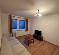 Nappali egy kétszobás lakásban kanapéval, televízióval és fa dekorációjú padlóval.