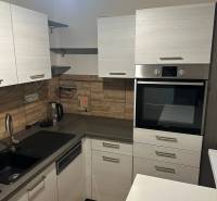 Konyha egy kétszobás lakásban, fa dekoros padlóval és beépített sütővel.