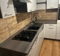 Konyha egy kétszobás lakásban gáz tűzhellyel, modern csempével és fa dekorációjú padlóval.