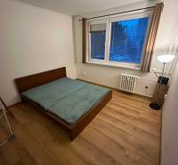 Hálószoba egy kétszobás lakásban, ággyal és fa dekor padlóval.