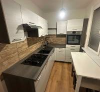 Konyha egy kétszobás lakásban, fa dekoros padlóval és téglafalakkal.