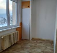 Világos szoba egy kétszobás lakásban, fa dekor padlóval és radiátorral.