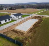 A családi ház alapjai Sokolovciban, mezők és szomszédos házak által körülvéve.