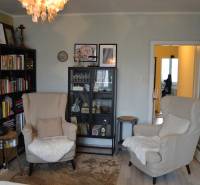 Nappali egy háromszobás lakásban könyvespolcokkal és fa mintázatú padlóval.