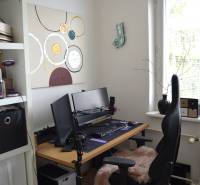 Iroda sarok egy háromszobás lakásban számítógéppel és dekorációkkal a falon.