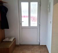 Családi ház belső tere üvegajtókkal és fa mintázatú padlóval.