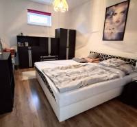 Hálószoba családi házban fa dekor padlóval, ággyal és fekete bútorokkal.