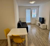 Nappali egy kétszobás lakásban fa dekor padlóval és világos ülőgarnitúrával.