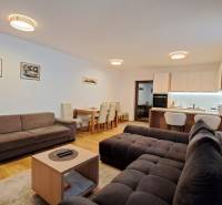 Nappali egy kétszobás lakásban kanapékkal, étkezőasztallal és konyhával, fa dekorációjú padlóval.