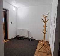 Folyosó egy kétszobás lakásban, fa dekoros padlóval, radiátorral és fogassal.