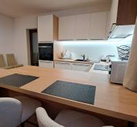 Konyha egy kétszobás lakásban beépített készülékekkel és fa hatású padlóval.