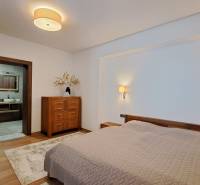 Hálószoba egy kétszobás lakásban ággyal, fa bútorokkal és fa dekorációjú padlóval.