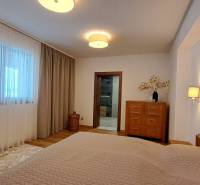 Hálószoba egy kétszobás lakásban fa dekorációval, függönyökkel és világos bútorokkal.