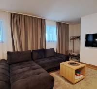 Nappali egy kétszobás lakásban kényelmes kanapéval és fa dekorációjú padlóval.