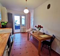 Konyha egy 4 szobás lakásban csempével, étkezőasztallal és vázában virágokkal.