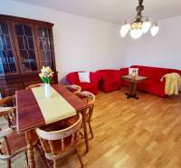 Fa vitrin, piros ülőgarnitúra és virágos étkezőasztal egy 4 szobás lakásban.