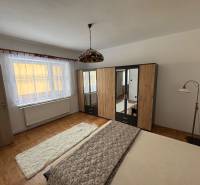 Hálószoba családi házban, fa dekorációjú padlóval, ággyal és ruhásszekrénnyel.