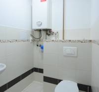 Fürdőszoba egy kétszobás lakásban kazánnal és WC-vel, kerámia csempével burkolva.