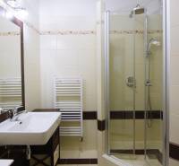 Fürdőszoba zuhanyzóval és mosdóval egy kétszobás lakásban, járólappal.