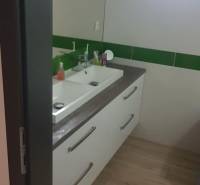 Fürdőszoba egy családi házban mosdókagylóval és fa dekorációjú padlóval.