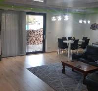 Nappali egy családi házban, fa mintázatú padlóval, kanapéval és étkezőasztallal.