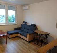 Nappali egy egyszobás lakásban fa mintás padlóval, kanapéval és asztallal.