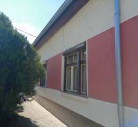 Családi ház Érsekújváron szigetelt homlokzattal és hálókkal, valamint fával a járda mellett.