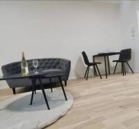 Nappali tér egy egyszobás lakásban kanapéval, asztallal és fa dekor padlóval.