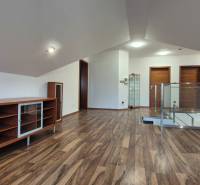 Családi ház tetőtéri helyisége fa dekoros padlóval és beépített szekrényekkel.