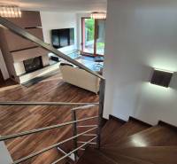 Nappali kandallóval és lépcsővel egy családi házban, fa dekorációjú padlóval.