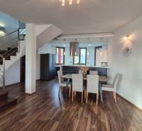 Családi ház belső tere konyhával, étkezővel és lépcsővel, fa dekorral a padlón.