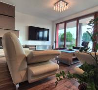 Nappali családi házban bőrkanapéval, kandallóval, televízióval és fa dekorációjú padlóval.