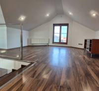 Tetőtéri szoba fa dekorációjú padlóval, lépcsővel és nagy ablakkal.