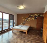 Szoba egy családi házban fa hatású padlóval, franciaággyal és terasszal.