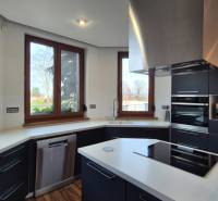 Családi ház konyhája fehér munkalappal, fekete szekrényekkel és készülékekkel.