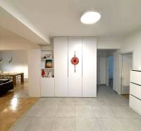 Folyosó egy 4 szobás lakásban fehér beépített szekrényekkel és kerámia padlólapokkal.