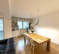 Étkezőasztal egy négy szobás lakásban, fa dekorral ellátott padlóval és fehér székekkel.