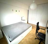 Hálószoba beépített szekrényekkel, fa dekorációjú padlóval és egyszerű bútorokkal egy 4 szobás lakásban.