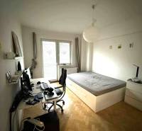 Hálószoba egy négy szobás lakásban, íróasztallal és ággyal, fa dekorú padlóval.