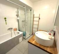 Fürdőszoba káddal, zuhanyzóval és mosdóval egy fa pulton a négy szobás lakásban.