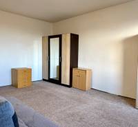 Egy szoba egy egyszobás lakásban komóddal, szekrénnyel és szőnyeggel a padlón.