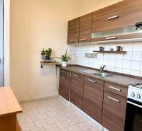 Konyha konyhapulttal és tűzhellyel egy egyszobás lakásban, világos csempék, fa dekoráció.