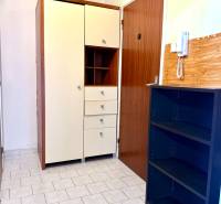 Az egyszobás lakás folyosója csempével, szekrényekkel és telefonnal a falon.