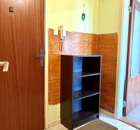 Egy szobás lakás előszobája szekrénnyel, csempével és telefonnal a falon.