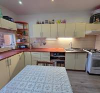 Konyha egy háromszobás lakásban krémszínű konyhabútorral és fa mintázatú padlóval.