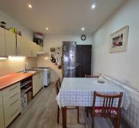 Konyha egy háromszobás lakásban, fa dekorációjú padlóval és étkezőasztallal.