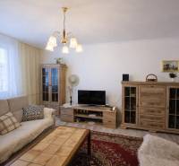 Nappali egy háromszobás lakásban fa dekorációval és kényelmes ülőgarnitúrával.