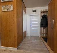 Folyosó a háromszobás lakásban fa dekorációval és fogasfallal.